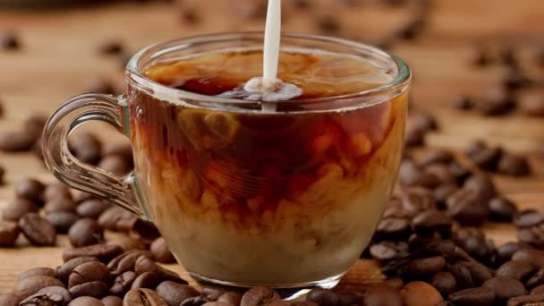 ミルクの流れが一杯のコーヒーに注ぎ込まれ そこに溶け込む キッチンテーブルのグラスコーヒーまたはティーカップを閉じます 朝の儀式 朝食のコンセプト スローモーション — ストック動画
