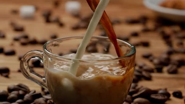 一串串的咖啡和牛奶倒入杯子 倒入一杯芬芳的饮料 在靠近咖啡豆的厨房桌子上 关上一杯咖啡或奶茶 早餐概念 — 图库视频影像