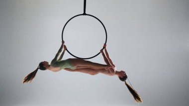 Modern koreografi ve akrobasi yaratıcı reklam konsepti. Beyaz stüdyo arka planında iki kadın jimnastikçi izole edilmiş. Hava dansçıları halkada halkalarla birlikte elementleri gösteriyorlar.