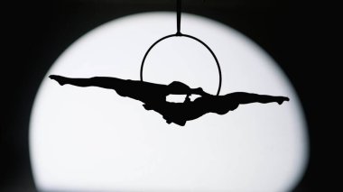 Modern koreografi ve akrobasi yaratıcı reklam konsepti. Siyah stüdyo arka planında iki kadın jimnastikçi izole edilmiş. Kızlar hava dansçıları siluetleri spot ışıklarında kayışlarla ringde dönüyorlar.