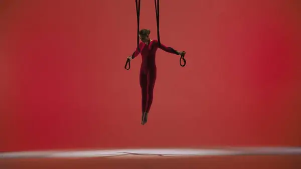 现代编舞和杂技创意广告的概念 女体操运动员被隔离在红色的工作室背景下 身披紧身衣 身披杂技服 身带表演元素的女子空中舞者 — 图库照片