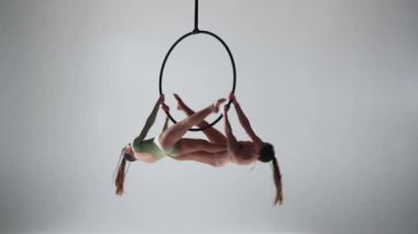 Modern koreografi ve akrobasi yaratıcı reklam konsepti. Beyaz stüdyo arka planında iki kadın jimnastikçi izole edilmiş. Hava dansçıları halkada halkalarla birlikte elementleri gösteriyorlar.