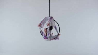 Modern koreografi ve akrobasi yaratıcı reklam konsepti. Beyaz stüdyo arka planında iki kadın jimnastikçi izole edilmiş. Parlak elbiseli kızlar ringde dans ediyorlar..