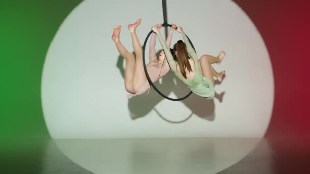 現代の振付とアクロバットクリエイティブ広告コンセプト 赤い緑のスタジオの背景に隔離された2人の女性ジムナスト ストラップ付きリング上のアクロバット要素を示す少女の空中ダンサー — ストック動画