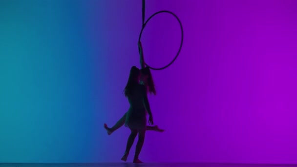 現代の振付とアクロバットクリエイティブ広告コンセプト 紫色のネオンスタジオの背景に隔離された2人の女性ジムナスト 少女空中ダンサーのシルエットはストラップ付きのリング上の要素を示します — ストック動画