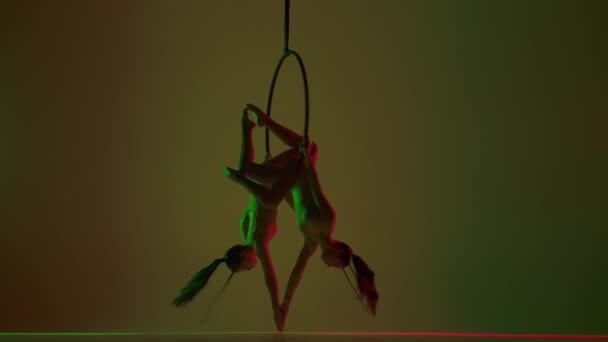 現代の振付とアクロバットクリエイティブ広告コンセプト イエロースタジオで隔離された2人の女性ジムナスト ストラップ付きのリングで頭を回転する少女空中ダンサー — ストック動画