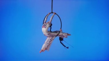 Modern koreografi ve akrobasi yaratıcı reklam konsepti. Kadın jimnastikçiler mavi neon stüdyo arka planında izole edilmiş. Kız ikilisi hava dansçıları halkada hava kayışlı elementler gösteriyor.