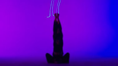 Modern koreografi ve akrobasi yaratıcı reklam konsepti. Kadın jimnastik düeti lazer mavisi neon stüdyo arka planında izole edildi. Kız dansçılar yerde jimnastik gösterisi yapıyorlar..