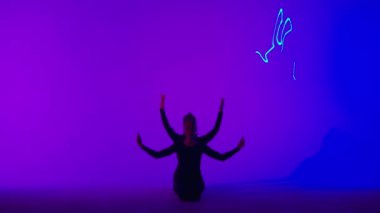 Modern koreografi ve akrobasi yaratıcı reklam konsepti. Kadın jimnastik üçlüsü lazer mavisi neon stüdyo arka planında izole edilmiş. Yerde jimnastik sanatsal öğeler gösteren kız dansçılar.