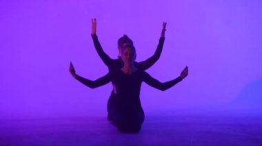 Modern koreografi ve akrobasi yaratıcı reklam konsepti. Kadın jimnastik üçlüsü lazer mavisi neon stüdyo arka planında izole edilmiş. Yerde jimnastik sanatsal öğeler gösteren kız dansçılar.