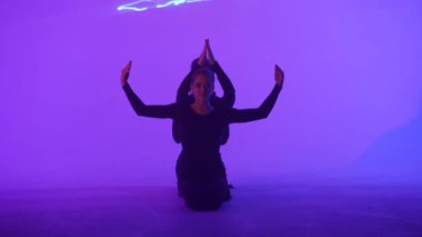 Modern koreografi ve akrobasi yaratıcı reklam konsepti. Kadın jimnastik üçlüsü lazer mavisi neon stüdyo arka planında izole edilmiş. Yerde jimnastik sanatsal öğeler gösteren kız dansçılar.