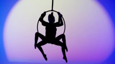 Modern koreografi ve akrobasi yaratıcı reklam konsepti. Mavi neon stüdyodaki kadın jimnastikçiler. Arka planda pembe spot ışıkları. Kızlar ikilisi hava dansçıları siluetleri halkada kayışlarla oturuyor..