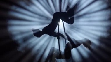 Modern koreografi ve akrobasi yaratıcı reklam konsepti. Siyah arka planda dumanlı iki kadın jimnastikçi. Kızları kapatın. Hava dansçıları halkada kemerli elementleri gösteriyorlar..
