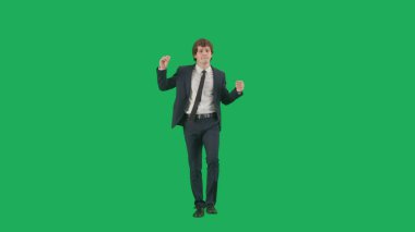 Modern iş adamı yaratıcı reklam konsepti. Krom anahtar yeşil ekran arka planda erkek modelin portresi. Şık takım elbiseli genç işadamı dans ediyor..