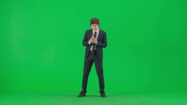 Modern iş adamı yaratıcı reklam konsepti. Krom anahtar yeşil ekranda erkek modelin portresi. Yakışıklı, şık takım elbiseli genç iş adamı elinde akıllı telefon mesajları ve danslar tutuyor.