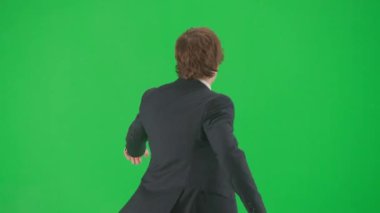 Modern iş adamı yaratıcı reklam konsepti. Krom anahtar yeşil ekran arka planda erkek modelin portresi. Havalı takım elbiseli şık genç işadamı yürüyüş ve dans ediyor.
