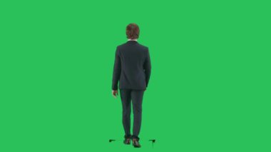 Modern iş adamı yaratıcı reklam konsepti. Krom anahtar yeşil ekranda izole edilmiş takım elbiseli erkek modelin arka planı. Takım elbiseli genç işadamı kameraya doğru yürüyor..