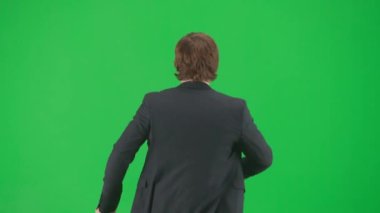 Modern iş adamı yaratıcı reklam konsepti. Krom anahtar yeşil ekran arka planda erkek modelin portresi. Modayı takip eden takım elbiseli arkadaş canlısı genç işadamı çantayla dans ediyor.