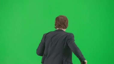 Modern iş adamı yaratıcı reklam konsepti. Krom anahtar yeşil ekran arka planda erkek modelin portresi. Havalı takım elbiseli şık genç işadamı yürüyüş ve dans ediyor.