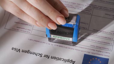 Pasaport ve göç yaratıcı reklam konsepti. Vize başvurusunu yakından çek. Avrupa Birliği vize belgesine üst düzey bir bakış açısı, kadın işçi üzerine onay damgası yapıştırıyor.