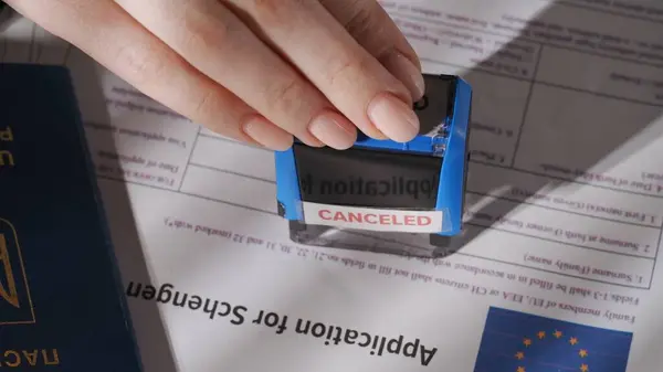 Pasaport ve göç yaratıcı reklam konsepti. Vize başvurusunu yakından çek. Avrupa Birliği vize belgesinin en üst görünümü, kadın çalışan üzerine iptal işareti yapıştırıyor.