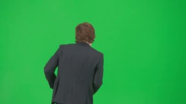 Modern iş adamı yaratıcı reklam konsepti. Krom anahtar yeşil ekranda erkek modelin portresi. Güzel takım elbiseli yakışıklı genç işadamı, komik disko dansı yapıyor..