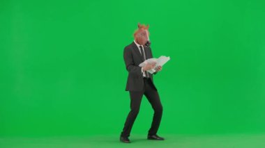 Yeşil stüdyo geçmişinde at kafalı maskeli bir iş adamı. Bir işadamı belgelere bakıyor ve neşeyle dans ediyor. Sıkı çalışma konsepti