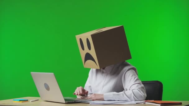 スタジオグリーンの背景に彼女の頭の上に否定的な絵文字のボール紙のボックスに女性 ノートパソコンを使ってビデオ通話で話し 彼女のハードワークについて文句を言う女性労働者 ビジネスライフ — ストック動画