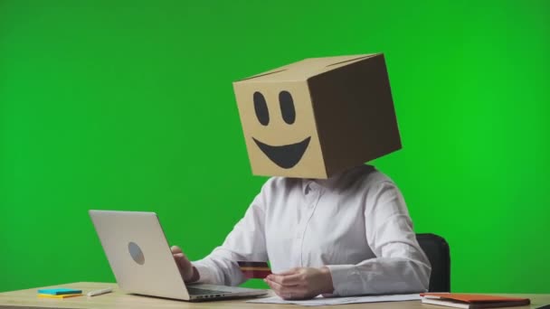 スタジオグリーンの背景に笑顔の絵文字のボール紙のボックスに女性 労働者は 銀行カードとラップトップを使用してオンラインで購入し 失敗にイライラし 絵文字を悲しい側に回します — ストック動画