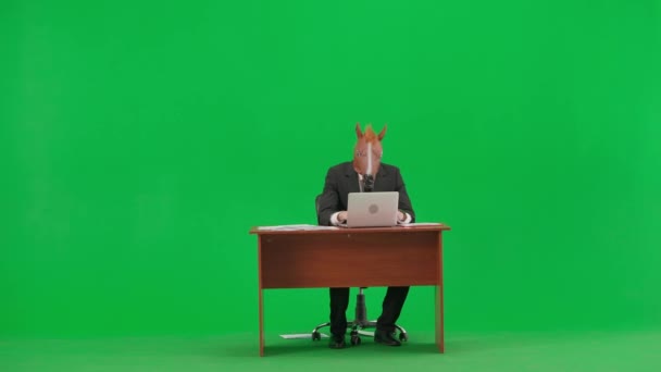 Mężczyzna Garniturze Końską Maską Zielonym Tle Studia Biznesmen Siedzący Przy — Wideo stockowe