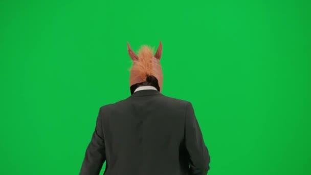 Mężczyzna Garniturze Końską Maską Zielonym Tle Studia Biznesmen Spaceruje Skacze — Wideo stockowe