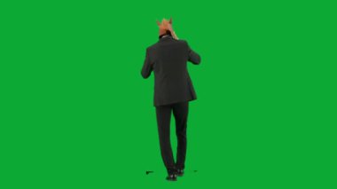 Yeşil stüdyo geçmişinde at kafası maskesi olan takım elbiseli bir adam. İş adamı akıllı telefondan konuşuyor ve yürüyor. Sıkı çalışma kavramı Geçmişe bakış