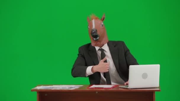 Mężczyzna Garniturze Końską Maską Zielonym Tle Studia Biznesmen Siedzi Przy — Wideo stockowe