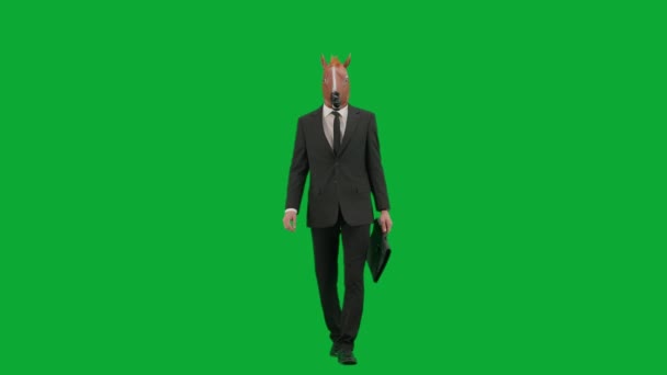 身穿西装 头戴马头面具 背景是绿色工作室 商人手里拿着黑手提箱走着 艰苦工作概念 — 图库视频影像