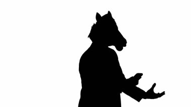 Beyaz stüdyo arka planında at kafası maskesi olan takım elbiseli siyah bir adam silueti. Bir iş adamı akıllı telefondan konuşuyor, sinirleniyor ve telefona doğru bağırıyor. Sıkı ofis işi kavramı