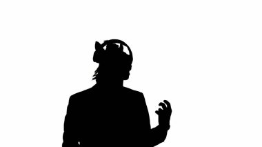 Beyaz izole edilmiş stüdyo arka planında at başlı maskeli iş adamı silueti. Bir iş adamı büyük kırmızı kulaklıklarla müzik dinler ve dans eder. Sıkı ofis işi kavramı