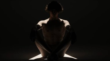 Vücut güzelliği ve sağlık hizmetleri yaratıcı reklam konsepti stüdyoda siyah arka planda erkek modelin portresi. Çekici bir adam silueti kameranın önünde poz veriyor..