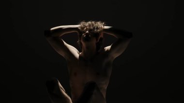 Vücut güzelliği ve sağlık hizmetleri yaratıcı reklam konsepti stüdyoda siyah arka planda erkek modelin portresi. Çekici adam silueti kameraya ışık altında poz veriyor..