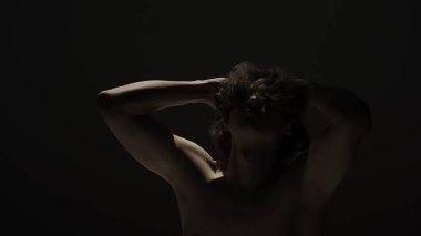 Vücut güzelliği ve sağlık hizmetleri yaratıcı reklam konsepti stüdyoda siyah arka planda erkek modelin portresi. Çekici adam silueti kameraya dokunuyor..