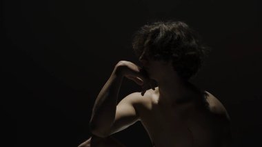 Vücut güzelliği ve sağlık hizmetleri yaratıcı reklam konsepti stüdyoda siyah arka planda erkek modelin portresi. Çekici erkek silueti kameranın çenesine dokunuyor..