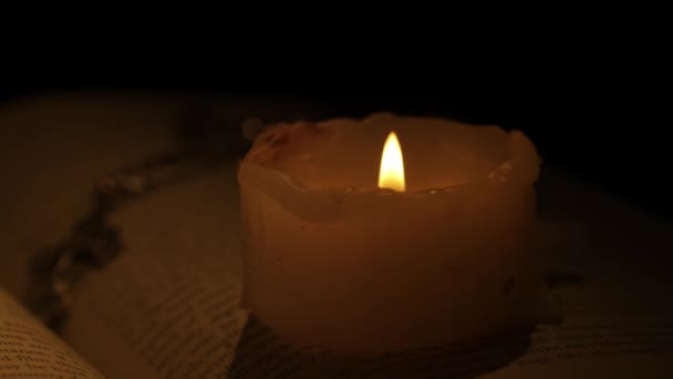历史文物和古董设计创意广告理念 在烛光下 近距离拍摄了一本背景黑暗的复古书籍 桌上翻开的书 书页上的蜡烛和十字架 — 图库视频影像