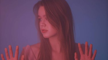 Güzellik ve kozmetoloji yaratıcı reklam konsepti. Buhar ve sis içinde cam pencerenin arkasında neon ışıklı kadın portresi. Makyajlı ve saçı cam üzerinde el ele duran bir kız..