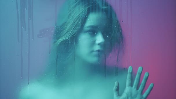 美容美感创意广告理念 在玻璃窗后面的霓虹灯下的女性画像 在蒸汽和水滴中 迷人的女孩手拉手在玻璃上看过去 — 图库视频影像