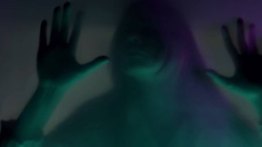 Paspas perdesinin arkasında, pembe ve yeşil neon ışıklı bir kadının bulanık silueti. Yaklaş. Bir kadın tırnaklarını bariyere sürtüyor, yırtmaya çalışıyor. Hayaletler ve ruhlar kavramı