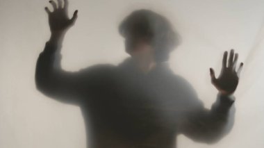 Donmuş camların ya da perdelerin arkasında sisli bir adam silueti. Adam bariyere elleriyle dokunarak kurtulmaya çalışıyor. Ölümden sonraki yaşam ve öteki dünya kavramı, hayaletler ve ruhlar.