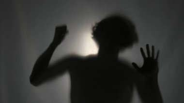 Matt 'in perdesinin arkasındaki karanlık siluet bir ışık huzmesi tarafından aydınlatılıyor. Adam görünmez bariyeri aşmaya çalışarak yumruğunu çırpıyor. Hayalet kavramı.