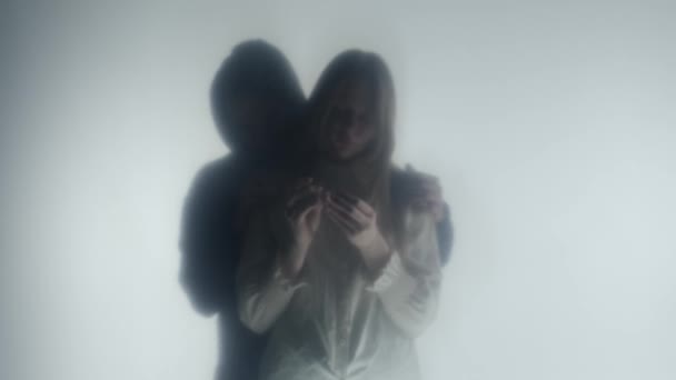 凍ったカーテンかガラスの後ろのカップルのシルエット 男は指輪を持っている悲しい女性の肩の周りに腕を置きます 幽霊の概念 愛する人の喪失 目に見えないサポート — ストック動画