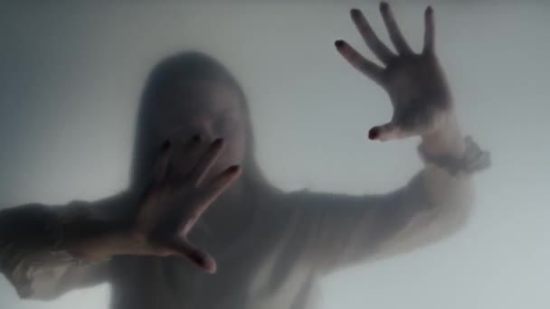 在结霜的窗帘或玻璃窗后面的雾气中的鬼魂妇女的轮廓 一个女人在摸杯子 来世的概念 另一个世界 — 图库视频影像