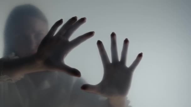 曇ったカーテンやガラスの後ろの霧の中の幽霊の女性のシルエット 手がガラスに触れると手が離れる 死後の世界 他の世界 幽霊の概念 — ストック動画
