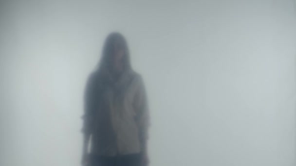 光と霧からアプローチすることは 女性のシルエットです 女性は凍ったガラスに近づき 彼女の手で触れ 回転し 光の中に離れて歩きます — ストック動画